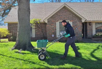 Technician spreading fertilizer on lawn